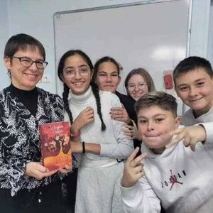 Mélodie Ducoeur, l'autrice, tenant son livre le royaume de Séraphin entre les mains et entourée de collégiens